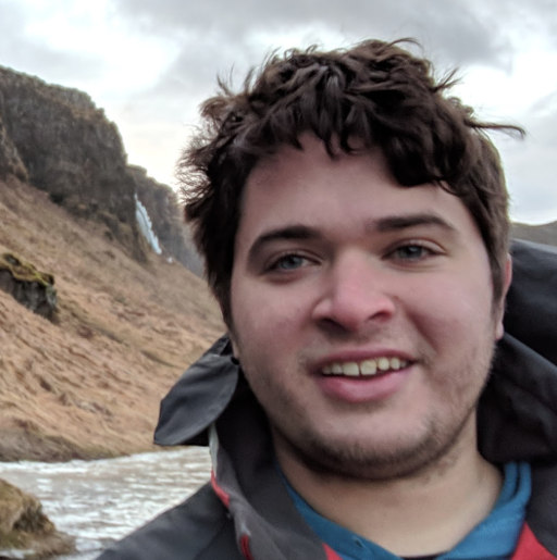 Portrait of a mathematician smiling. Foreground: white male, mid-20s, medium-length slightly shaggy brown hair, neck framed in hints of a coat. Background: icelandic peninsula in the winter, tundra covered in tan grass and multiple small frozen waterfalls in the background, very low cloud cover. We hope the accessibility is acceptable.